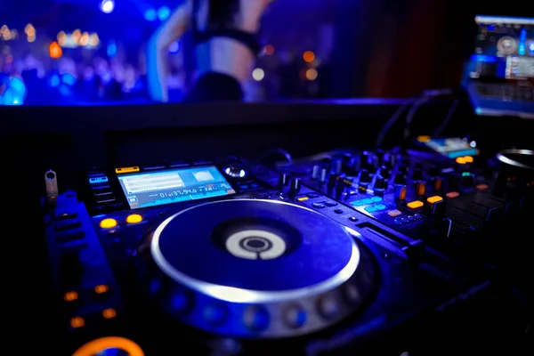 Disc Jockey mixing deck and turntables at night with colourful illuminated controls for mixing music for a party or disco