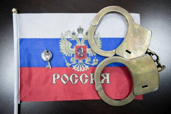 Russia flag  and police handcuffs. The concept of crime and offenses in the country