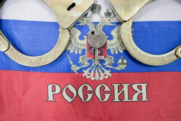 Russia flag  and police handcuffs. The concept of crime and offenses in the country