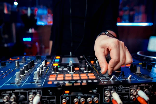 Dj mixes the track in the nightclub at a party. In the background laser light show