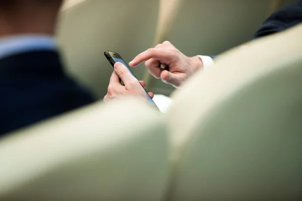 business people hands typing on smart phone during the seminar at conference room