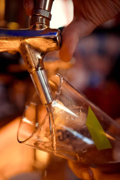 barman hand at beer tap pouring a draught lager beer serving in a restaurant or pub. Vintage soft effect on photo