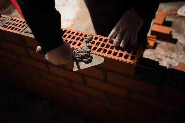 professional construction worker laying bricks and building barbecue in industrial site. Detail of hand adjusting