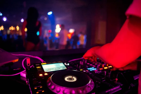 DJ behind the decks in a nightclub. DJ spinning plate. people dancing in a nightclub. disco