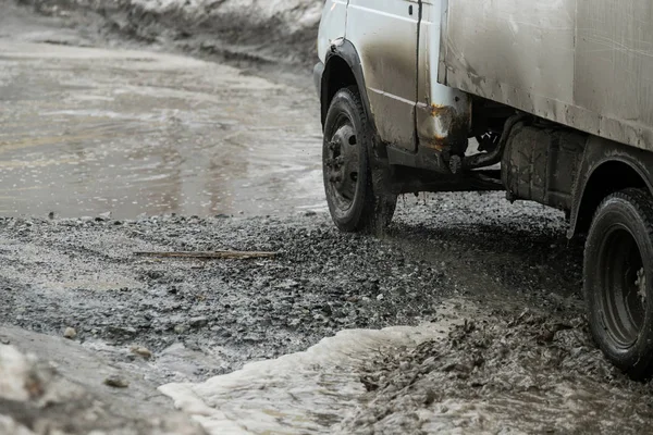 Poor road condotions - car wheel in melting show puddle.