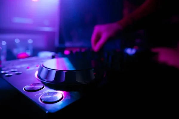 DJ mixing tracks on a mixer in a nightclub