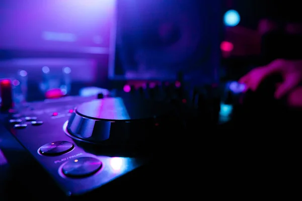 DJ mixing tracks on a mixer in a nightclub