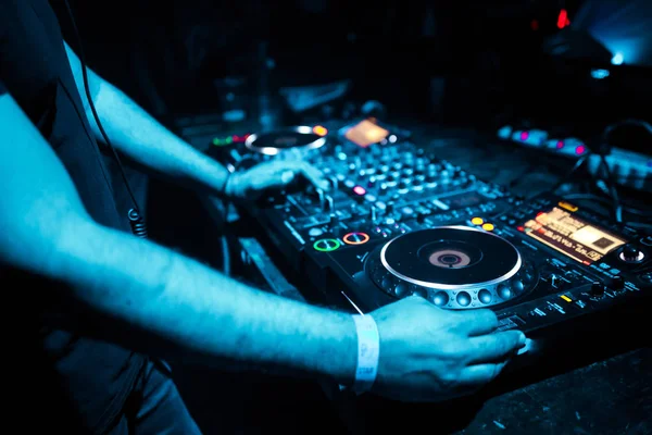 DJ mixing tracks on a mixer in a nightclub