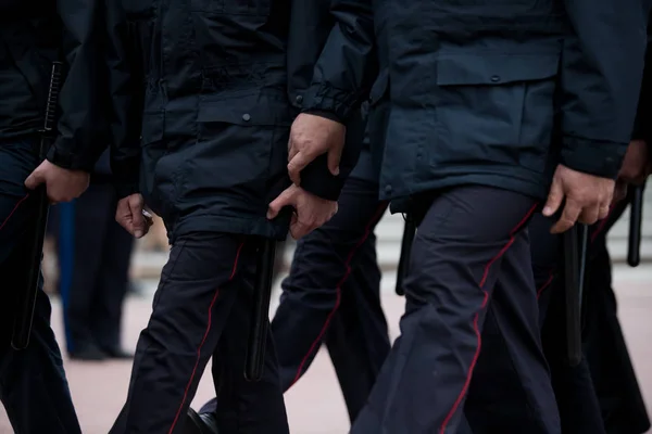 Russian police officers patrolling the street, rear view. Police officer holding a metal detector, security chec
