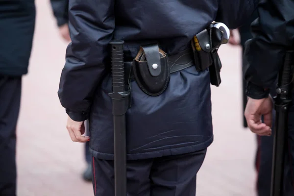 Russian police officers patrolling the street, rear view. Police officer holding a metal detector, security chec