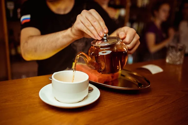 Process brewing tea,tea ceremony,Cup of freshly brewed black tea,warm soft light, darker background.