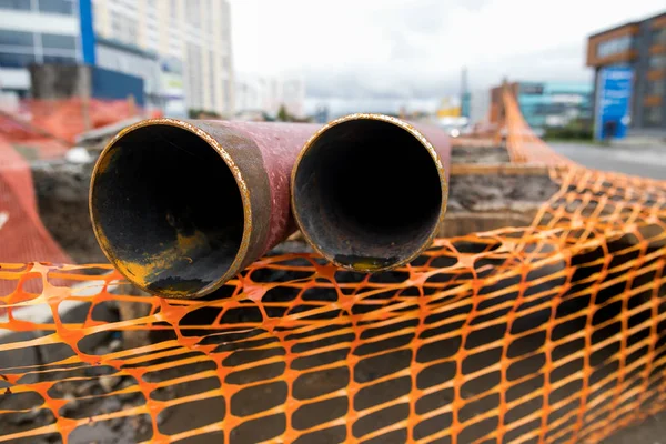 Laying or replacement of underground storm sewer pipes. Installation of water main, sanitary sewer, storm drain systems in city. Cast iron drainage pipe in ditch.