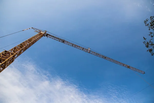 Construction site with cranes on sky background. Big yellow machinery construction crane tool of building industry for heavy lifting on blue sky background. Business engineering equipment modern