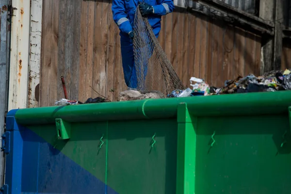 Garbage removal men working for a public utility emptying trash container