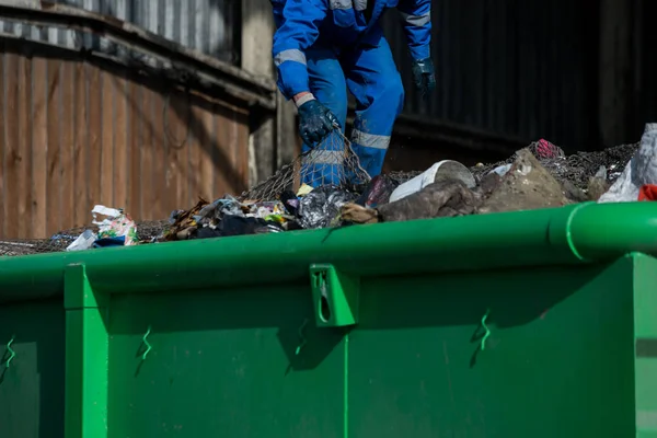 Garbage removal men working for a public utility emptying trash container