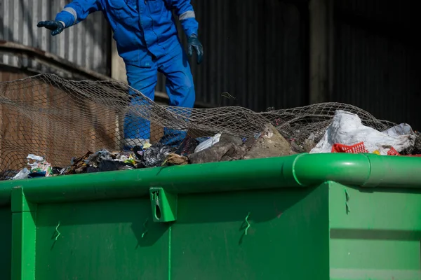 Garbage removal men working for a public utility emptying trash container