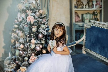 sevimli küçük kız stüdyoda beyaz elbise ve taç giyen Noel dekorasyonu ile poz