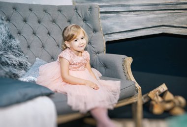 sevimli kız sarışın gri bir kanepe, Noel ve sıcak yılbaşı fotoğraf pembe elbiseli