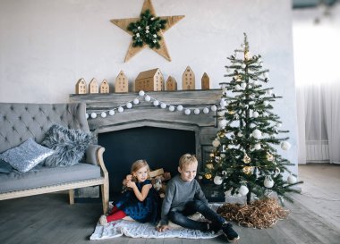 Çocuklarım - bir erkek ve bir kız şömine, yılbaşı ağacı, karton ev, rahat bir Noel dekor ve çocukların duyguları ile yürütme tarafından oturuyor musunuz