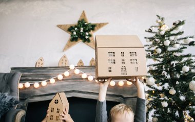 Çocuklarım - bir erkek ve bir kız şömine, yılbaşı ağacı, karton ev, rahat bir Noel dekor ve çocukların duyguları ile yürütme tarafından oturuyor musunuz