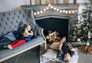 çocuklar - bir erkek ve bir kız şömine, Noel ağacı, karton ev, rahat Noel dekor ve çocuk duygular tarafından yalan söylüyorsun