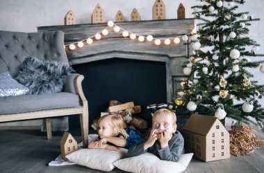 çocuklar - bir erkek ve bir kız şömine, Noel ağacı, karton ev, rahat Noel dekor ve çocuk duygular tarafından yalan söylüyorsun