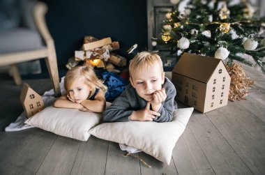 çocuklar - bir erkek ve bir kız şömine, Noel ağacı, karton ev, rahat Noel dekor ve çocuk duygular tarafından yalan söylüyorsun