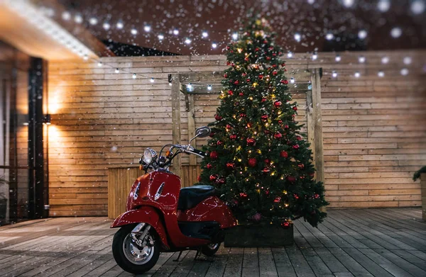 Bir yılbaşı masal ağacı ahşap bir teras üzerinde arka plan üzerinde kırmızı motosiklet