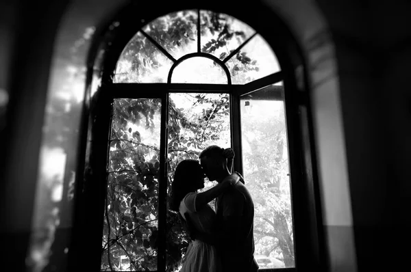 black and white photo of couple in love posing near window