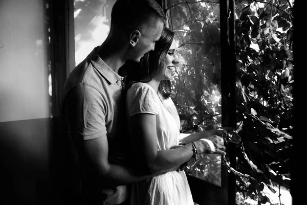 black and white photo of couple in love posing near window