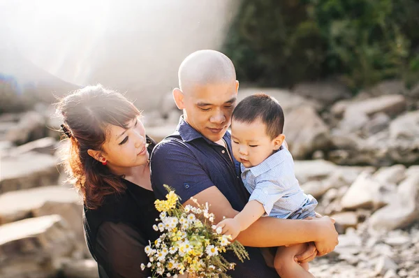 happy korean family on a walk near the river in the mountains, mom, dad and son asian laugh and hug