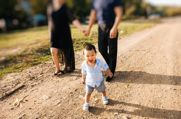 Asian family walking by field with little son