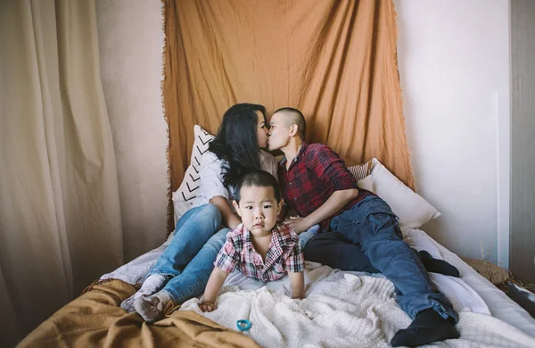 Korean family kissing on bed with son on foreground