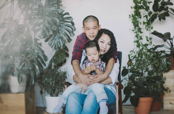 Korean family posing in studio sitting on chair at flower pots