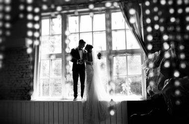 şık gelin ve Damat Düğün fotoğraf oturumunda stüdyo, aşık bir çift pencere yakın: