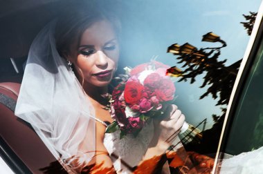 Güzel gelin elinde bir buket gül tutuyor.