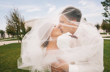 şık gelin ve Damat Düğün günü parkta bir yürüyüş üzerinde yakınındaki stadyum, uzun duvak