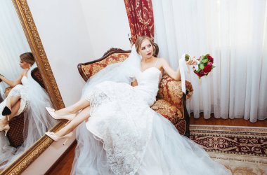 Gelin yaramazca onun elinde bir buket ile kırmızı bir sandalyede oturur