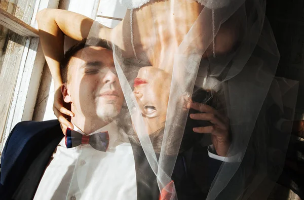 时尚的新郎新娘在演播室的婚礼照片会上 一对恋爱中的情侣躺在窗户附近的地板上 照片是在硬光下拍摄的 — 图库照片