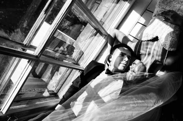 愛のカップルは窓の近くの床に横たわっているスタイリッシュなスタジオでウェディング フォト セッションで新郎新婦 写真はハードの光 — ストック写真