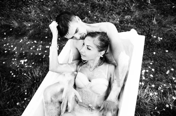 ブドウ畑の真ん中にバラの花びらをお風呂で 男と女が座っています — ストック写真