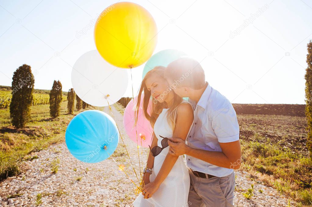 lovers laugh, hug and run through the fields for a walk in the summer, hold balloons