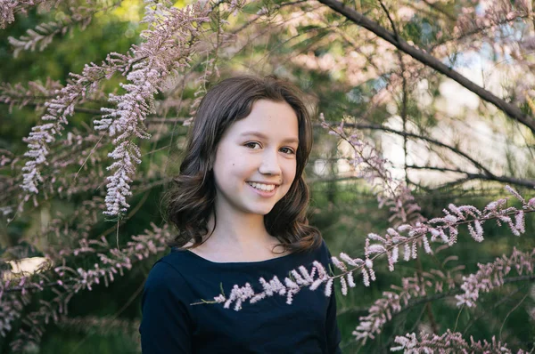 cute teen girl in flowering bushes for a walk, photo to the World Women\'s Day