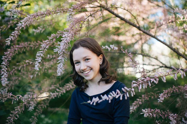 cute teen girl in flowering bushes for a walk, photo to the World Women's Day