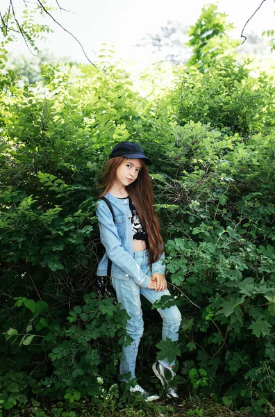 stock image red-haired teen girl in a denim suit posing in a green park, positive school girl