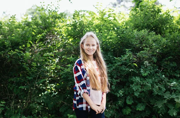 金发碧眼的少女穿着格子衬衫摆在一个绿色的公园 积极的女学生 — 图库照片