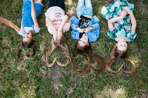 Μαλλιά Σχήμα Καρδιάς Τέσσερα Κορίτσια Εφήβων Είναι Ξαπλωμένη Στο Γρασίδι — Φωτογραφία Αρχείου