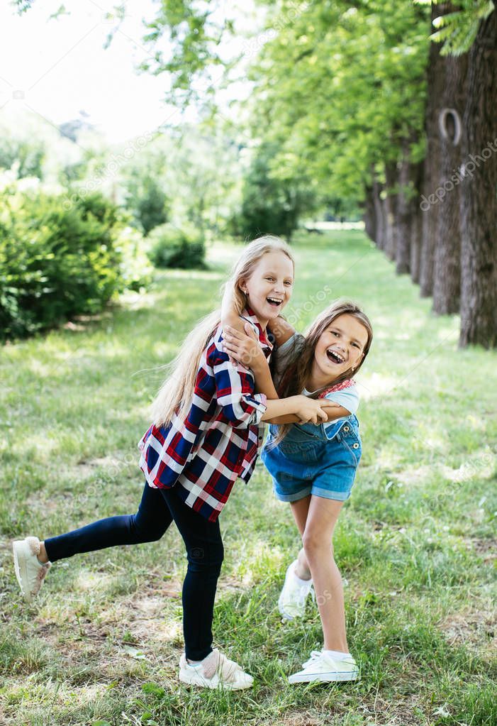 teen girls walk, laugh and play in a green park for a break, positive schoolgirl girlfriend