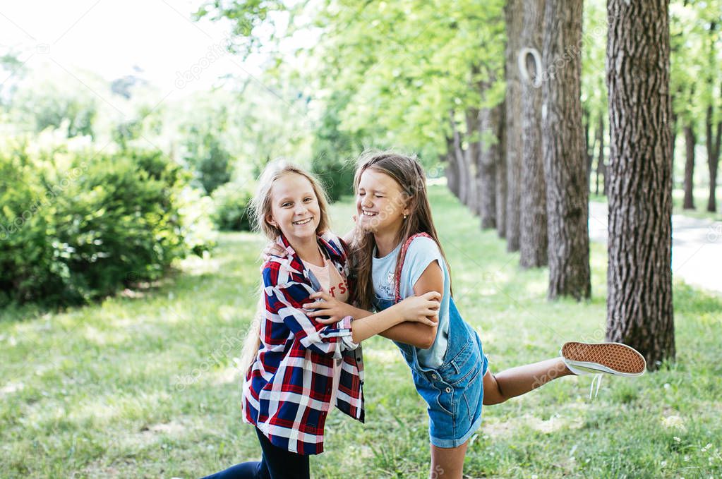 teen girls walk, laugh and play in a green park for a break, positive schoolgirl girlfriend