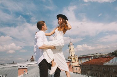 seven çift - beyaz elbise ve şapka ve bir adam bir kız - sarılma ve gülüyor, şehrin pozitif ve samimi duygular aşk yüksekliğini bir görünümden çatıda bir yolda